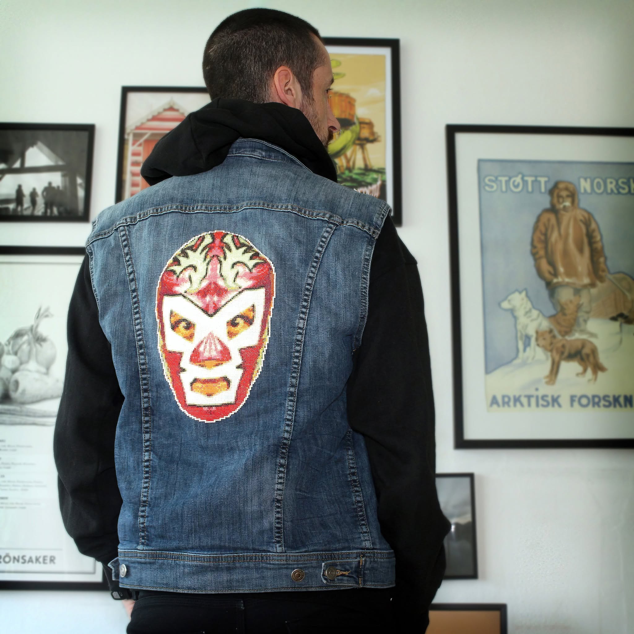 A cross-stitch depicting the mask of Dr Wagner Jr, attached to a denim jacket.